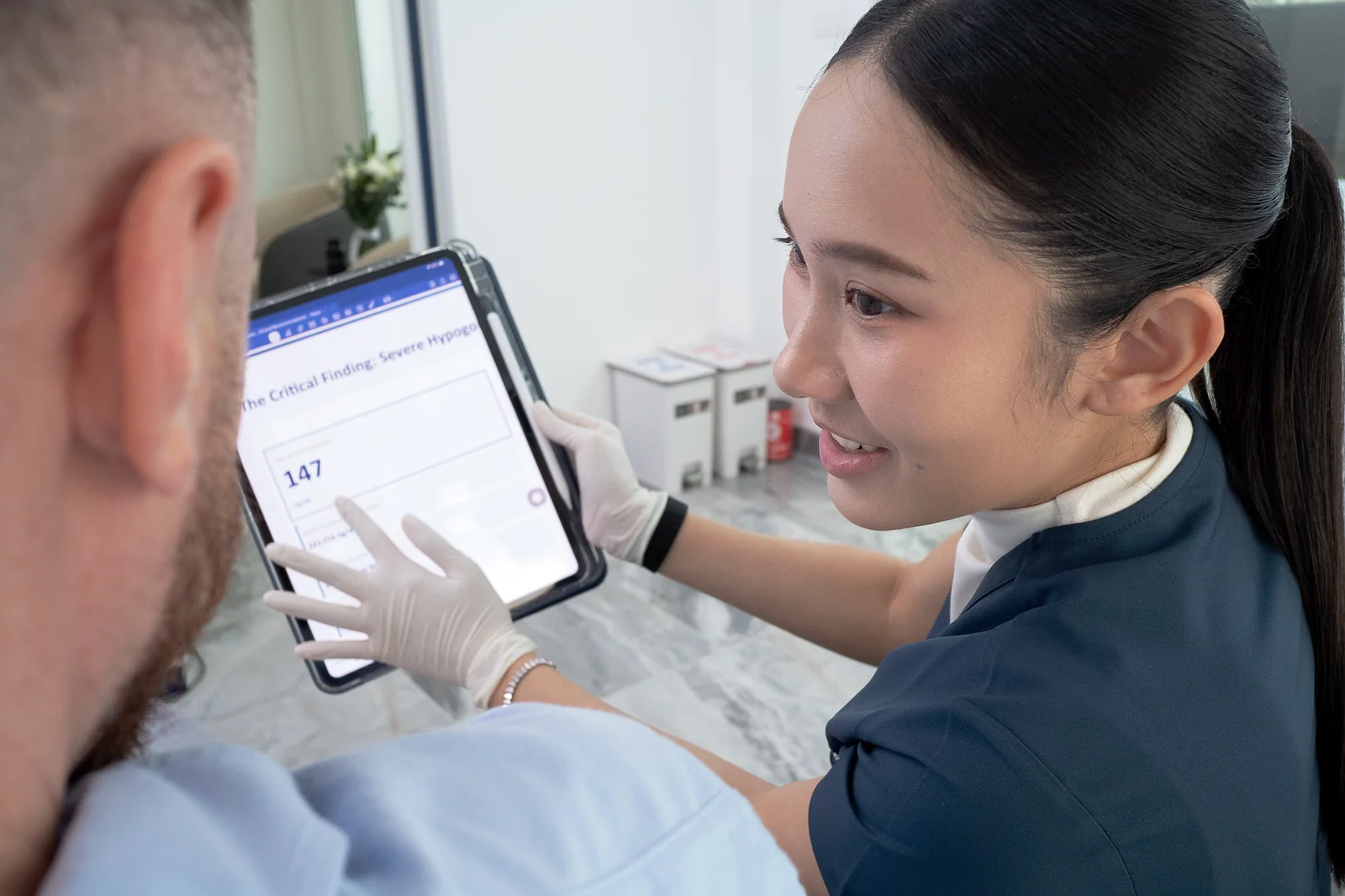 Dr. Kenika reviewing results on a tablet — doctor-led care across Thailand with the TRT Thailand app